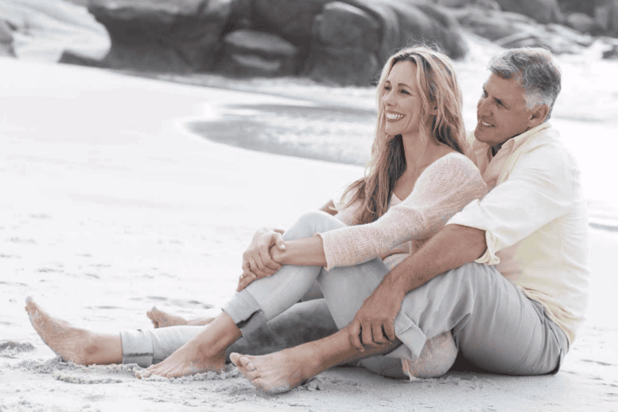 Mature man and woman sittting on the beach, cozy
