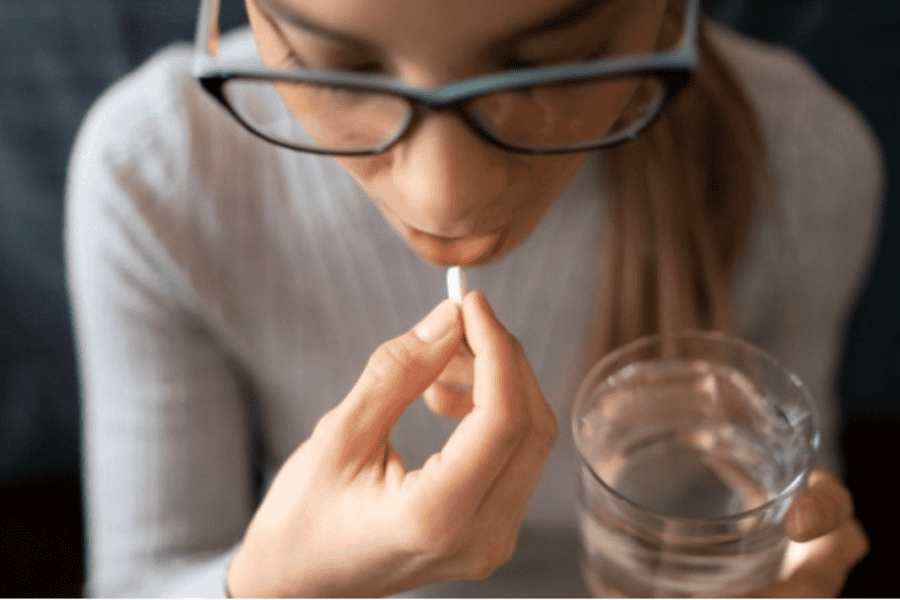Woman woth glasses taking a pill