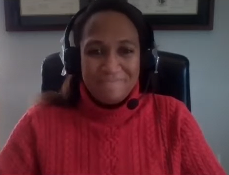 Dr. Angel Alexander-Martin wearing a red sweater, smiling and recording