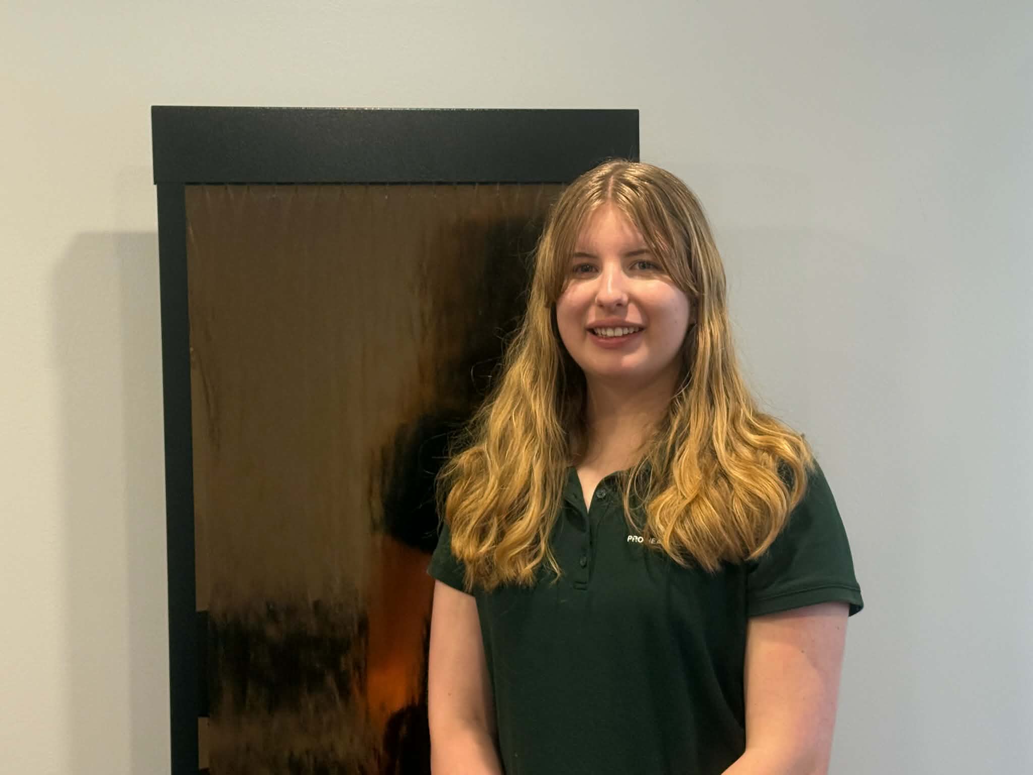 Medical Assistant Sophia in green shirt, standing in front of the fountain